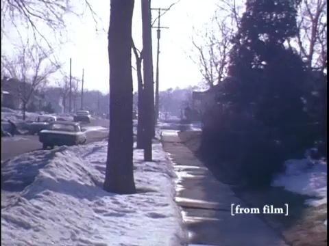 Two men casually conversing by a classic car parked in a wintry neighborhood.